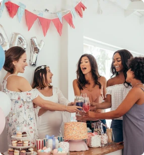 Zwei Frauen, eine schwanger, halten einen Teddybären und lächeln